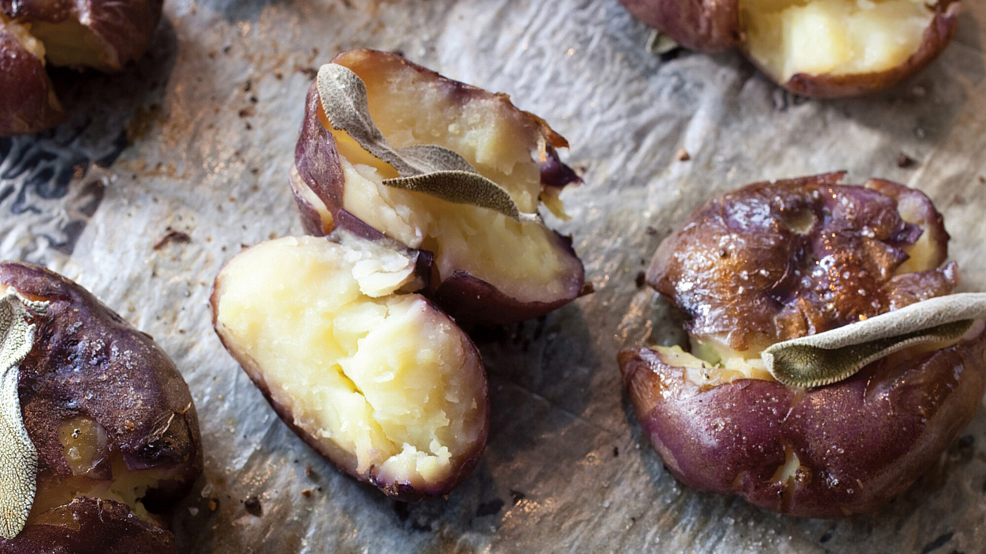 תפוחי אדמה שלמים מעוכים קלות ואפויים עם מרווה. צילום: דן לב | סגנון: אוריה גבע