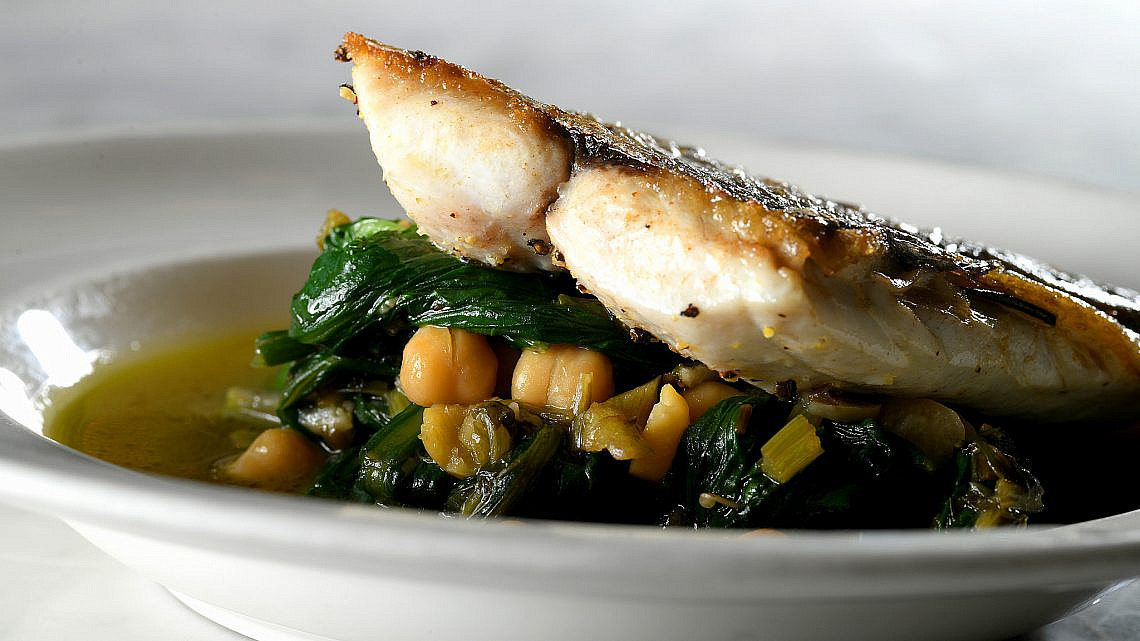 תבשיל עלים ירוקים עם חומוס ודג צלוי של שף עינב אזגורי. צילום: רן בירן