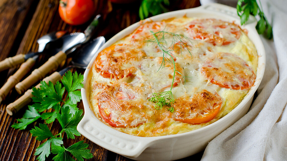 גראטן תפוחי אדמה, עגבניות ובצל בזיגוג טחינה.  צילום: Shutterstock